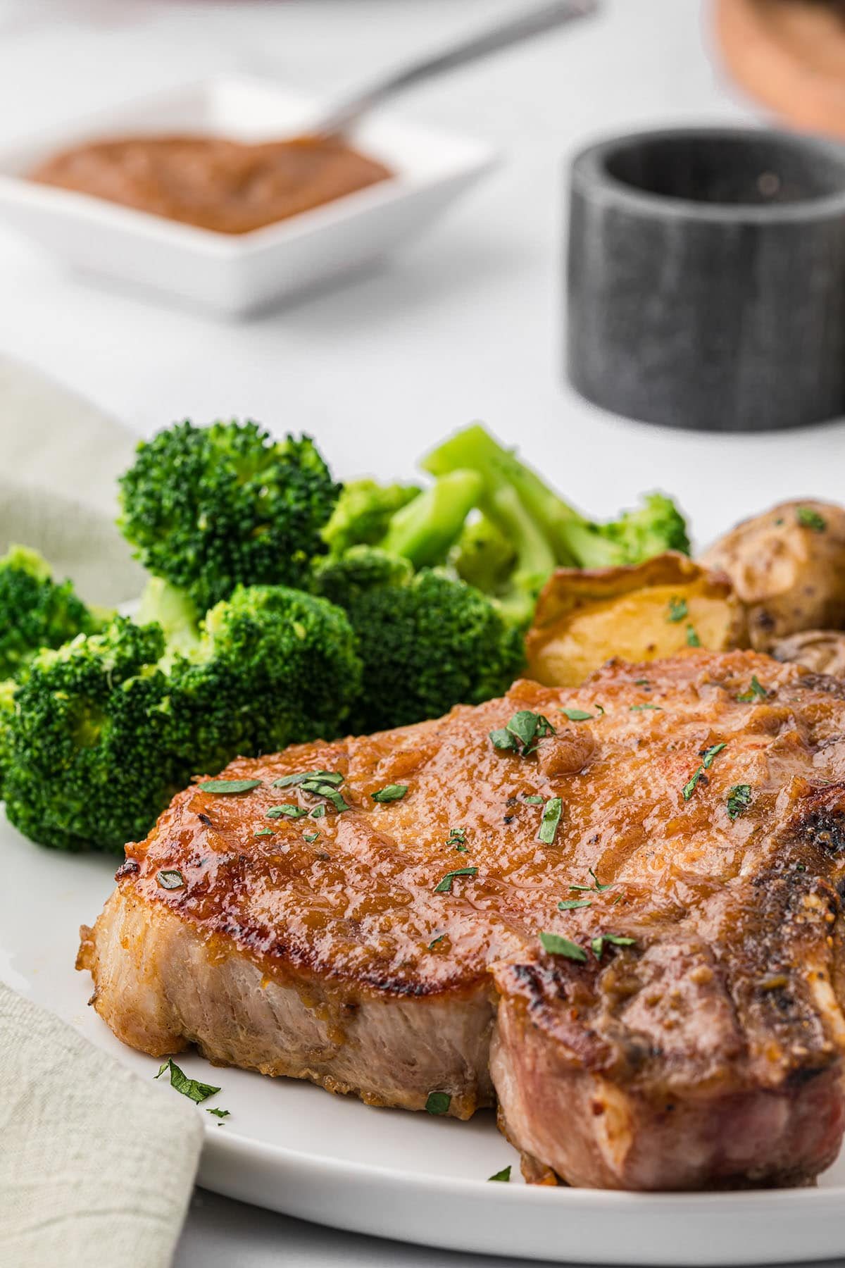 a plate with a glazed pork chop and steamed broccoli