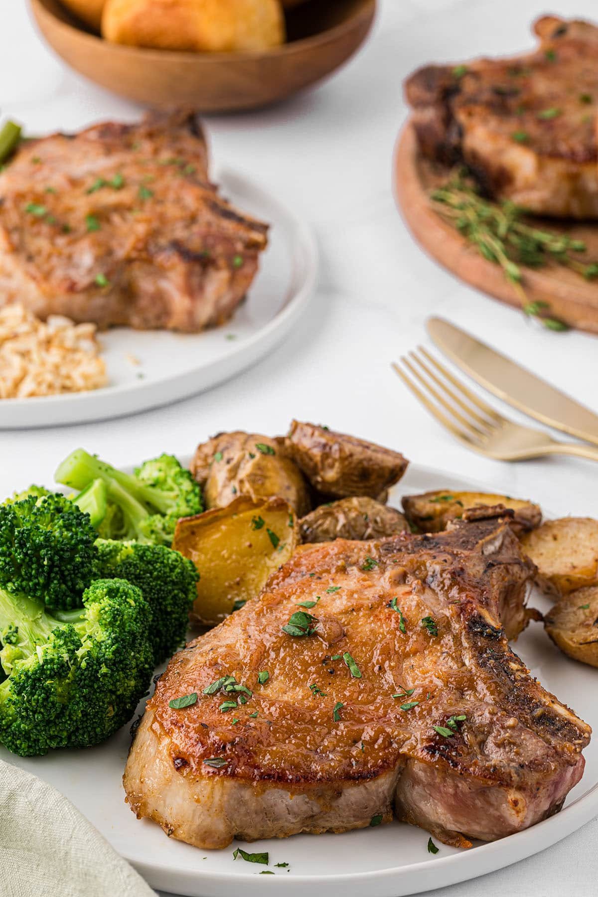 apple butter glazed pork chops on a plate with potatoes and broccoli on a dinner table
