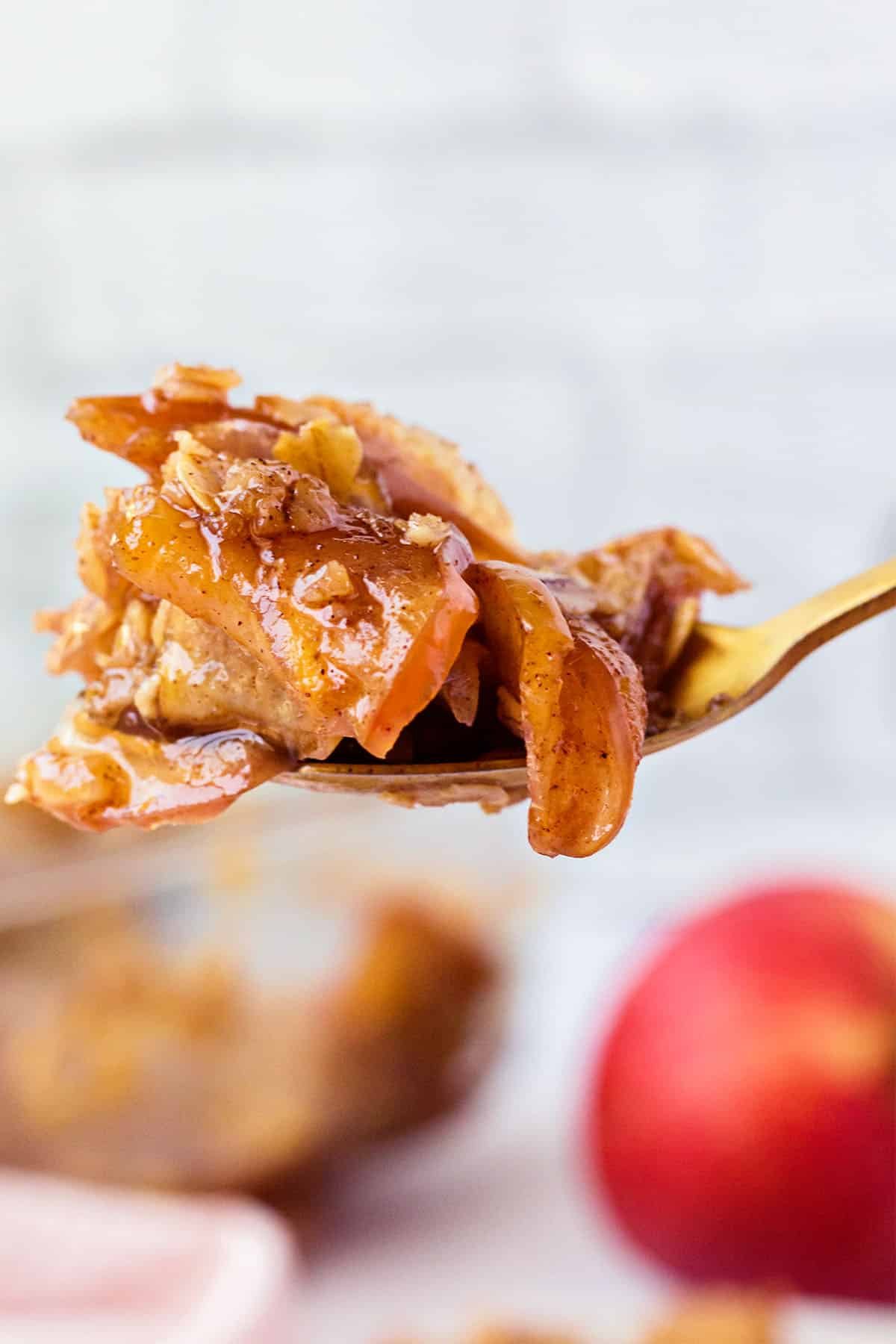 A gold spoon full of homemade apple crisp