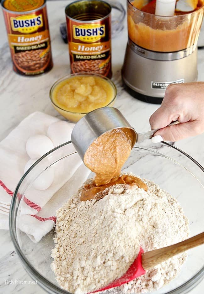 Mixing bowl pouring baked beans into muffin mixture for Apple Spice muffins