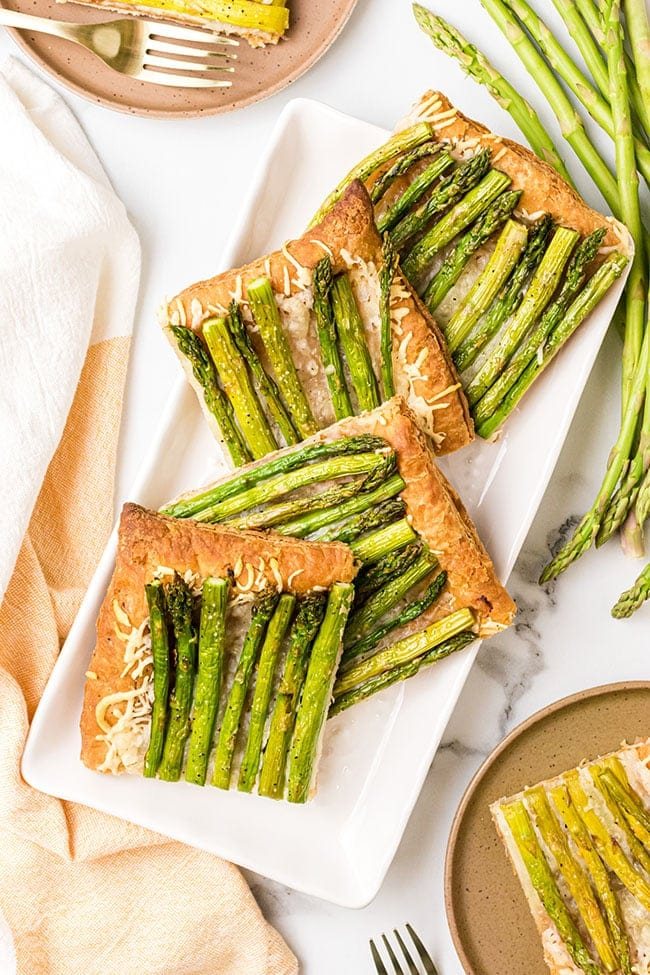 Asparagus tart with gruyere cut into servings on a white platter