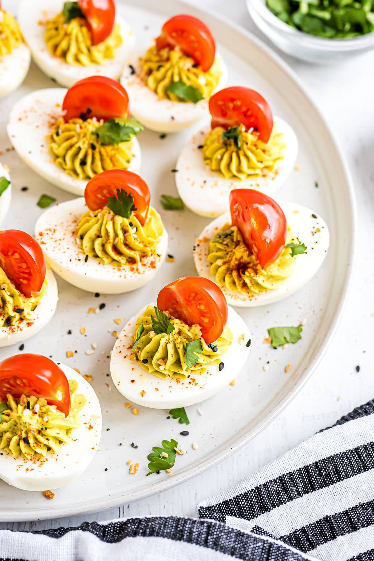 deviled egg appetizer om a white plate and a black and white towel.