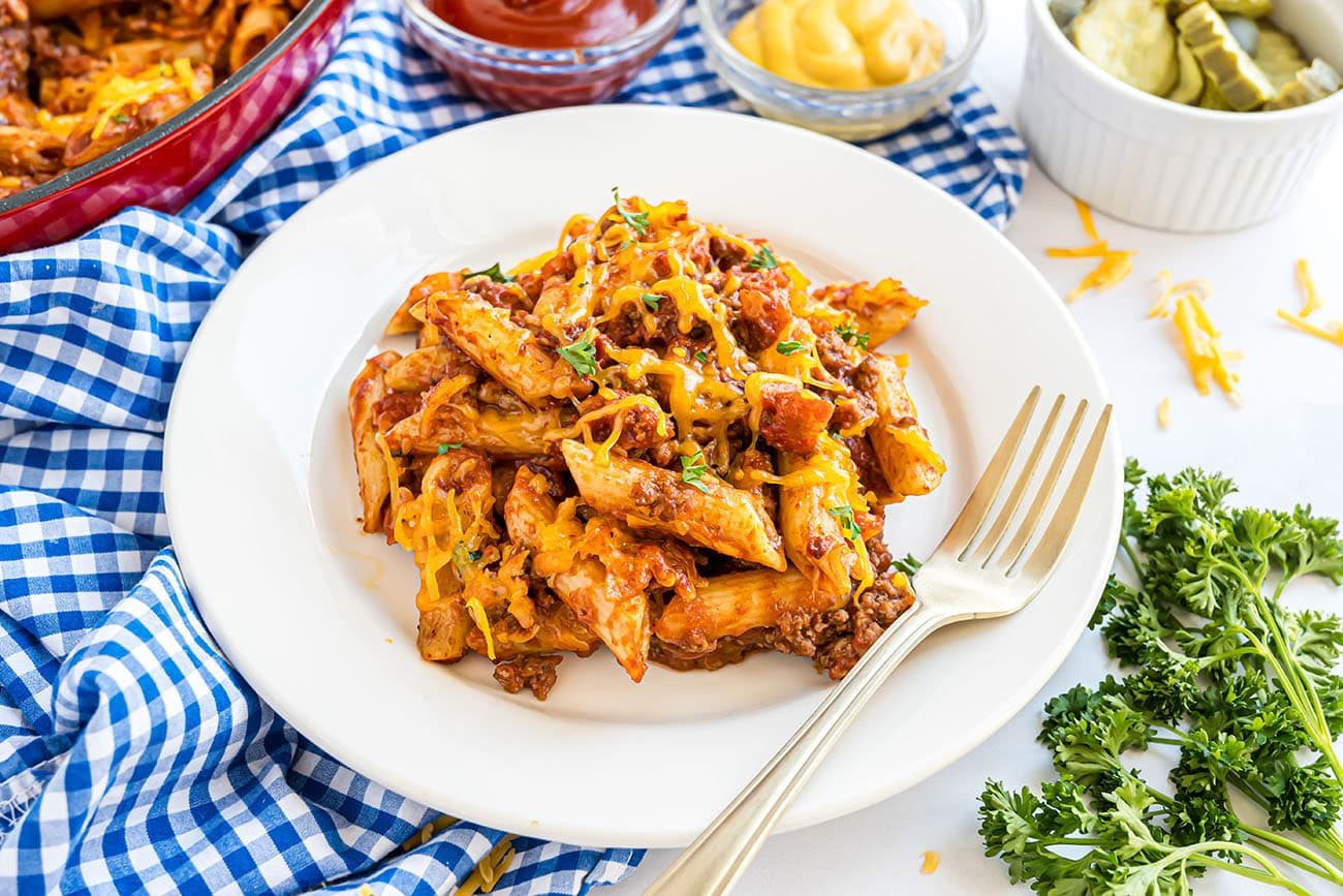 Close-up of pasta coated in cheesy sauce with bacon pieces and ground beef.