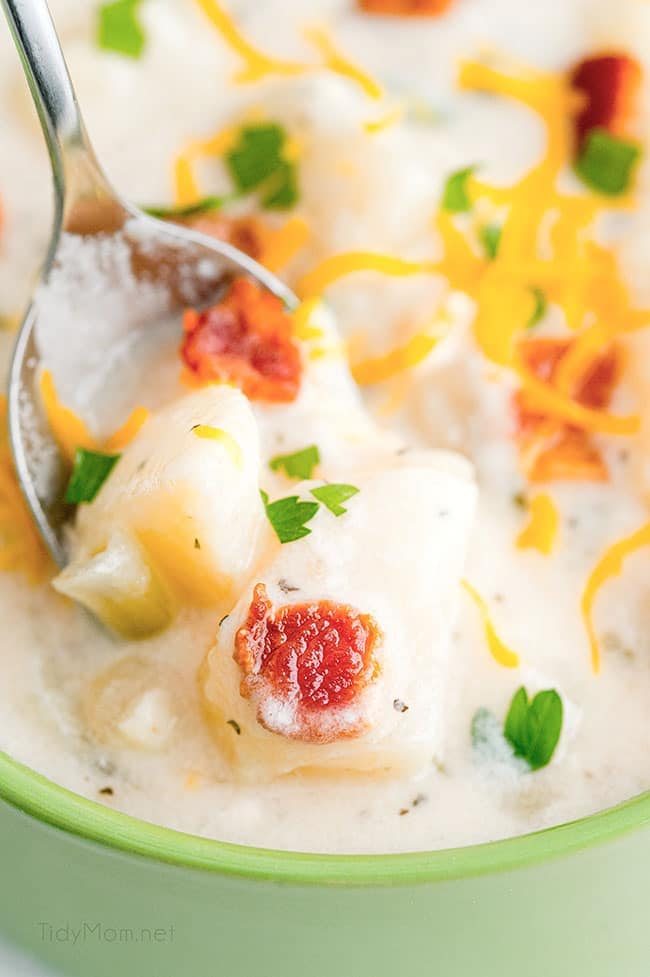 a spoon ful of bacon potato soup in a green bowl
