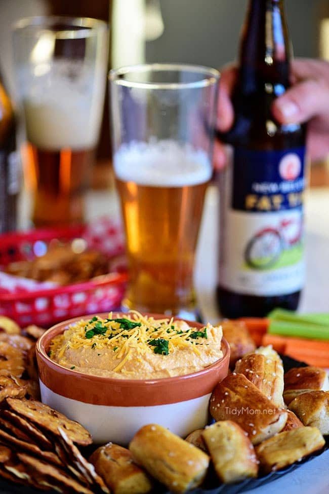 Pub-style Beer Cheese Dip with pretzels and glass and bottle of beer.