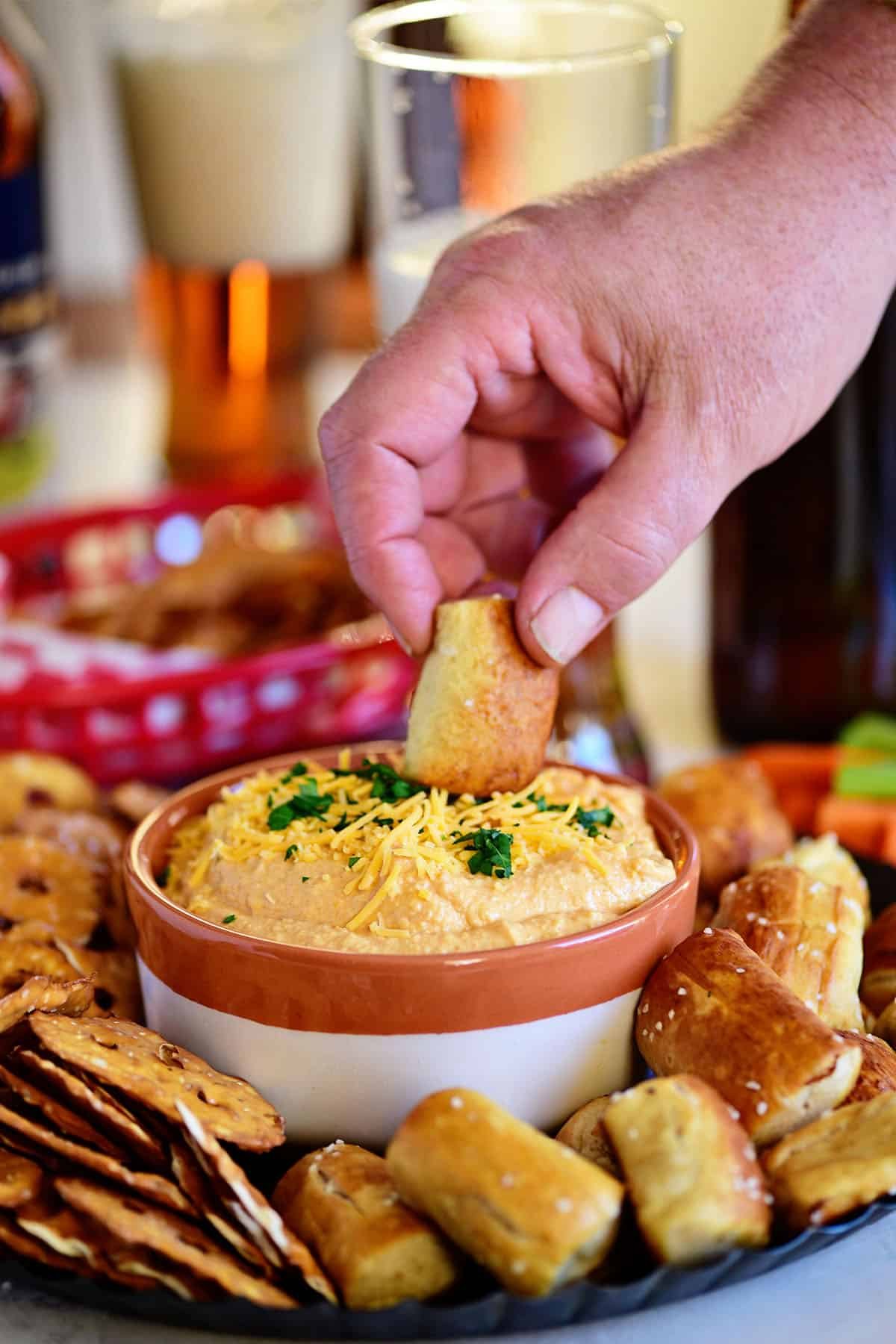 man dunking pretzel in beer cheese dip