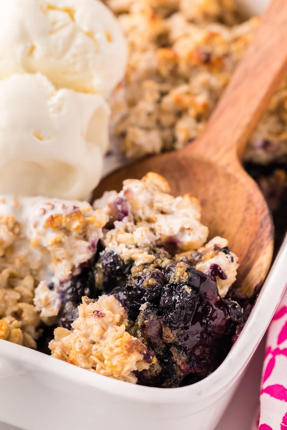 baking dish with fruit crisp and wooden serving spoon