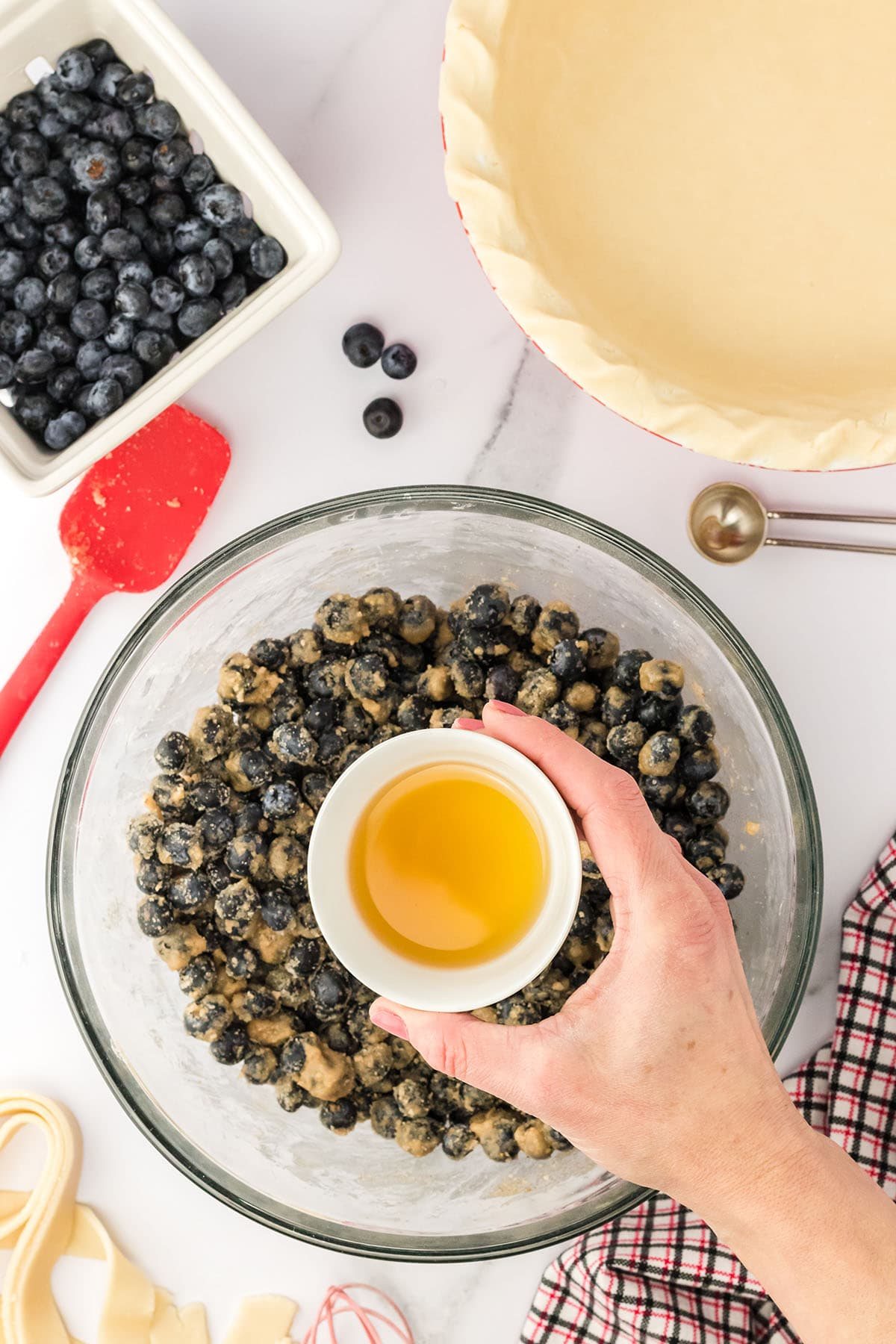 step two for making blueberry pie filling in a glass mixing bowl