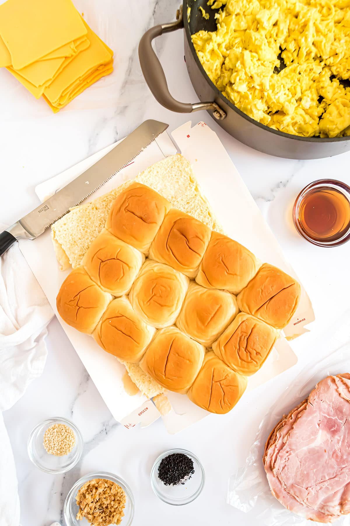Hawaiian rolls on a cutting board with a bread knife