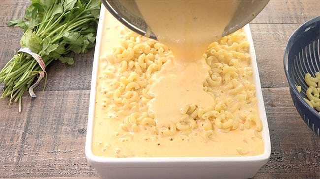 pouring cheese over mac ‘n cheese