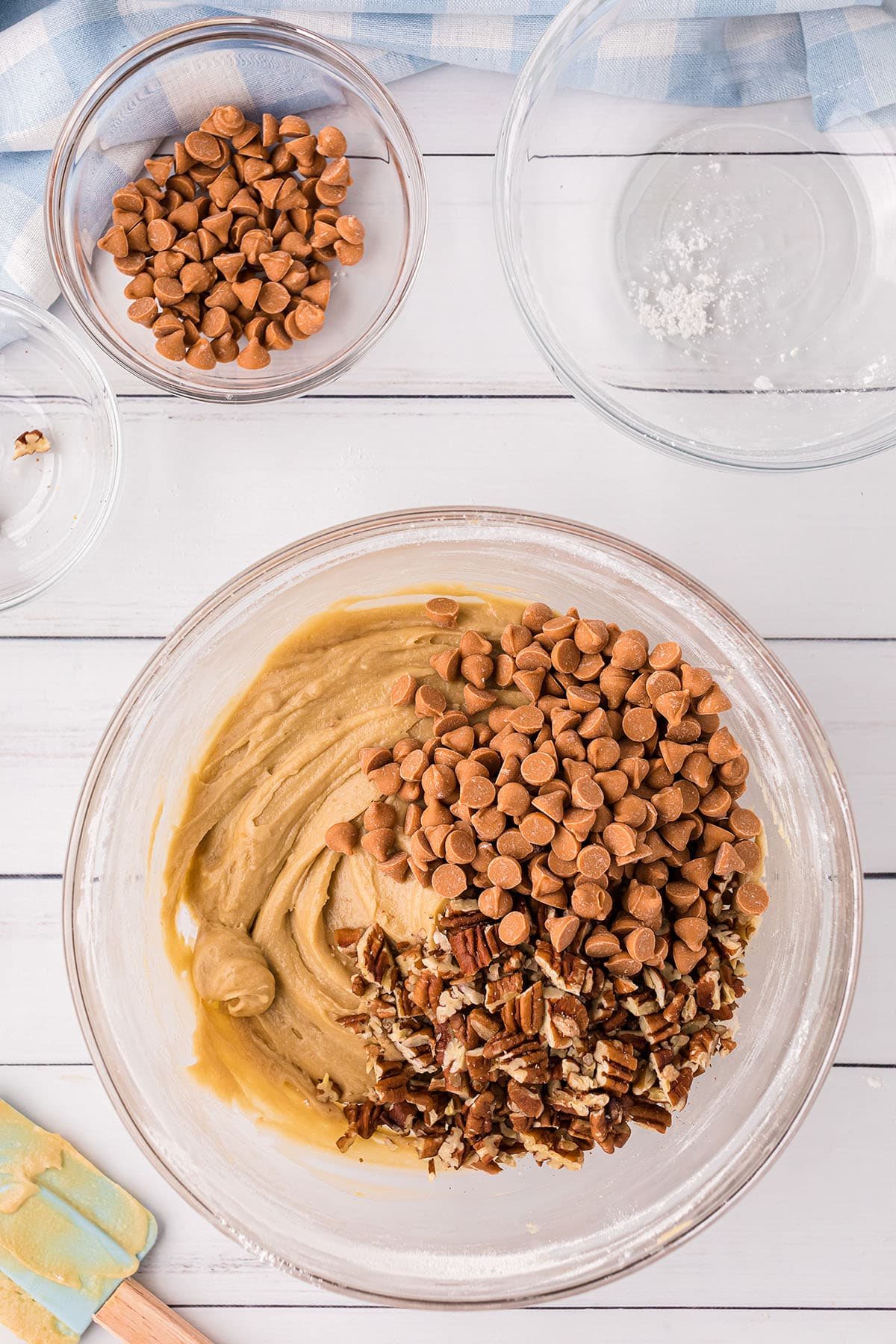 butterscotch brownie batter with butterscotch chips and peans in a glass mixing bowl