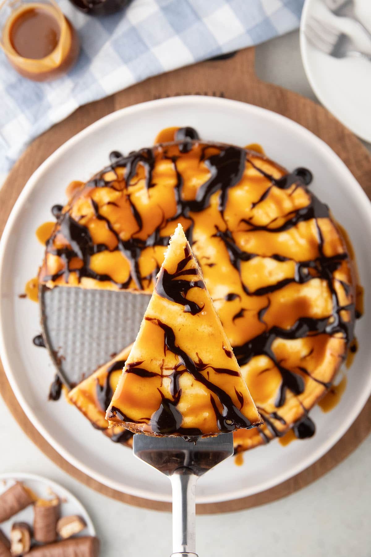 slice of cheesecake on a pie server over the candybar cake
