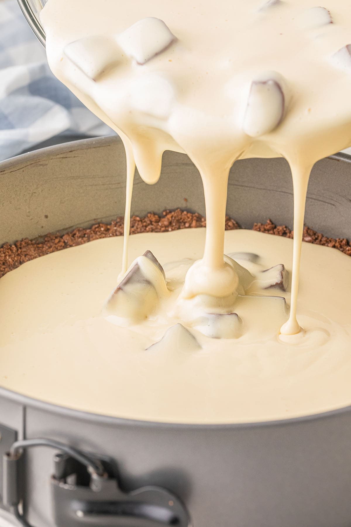pouring cheesecake batter into pan