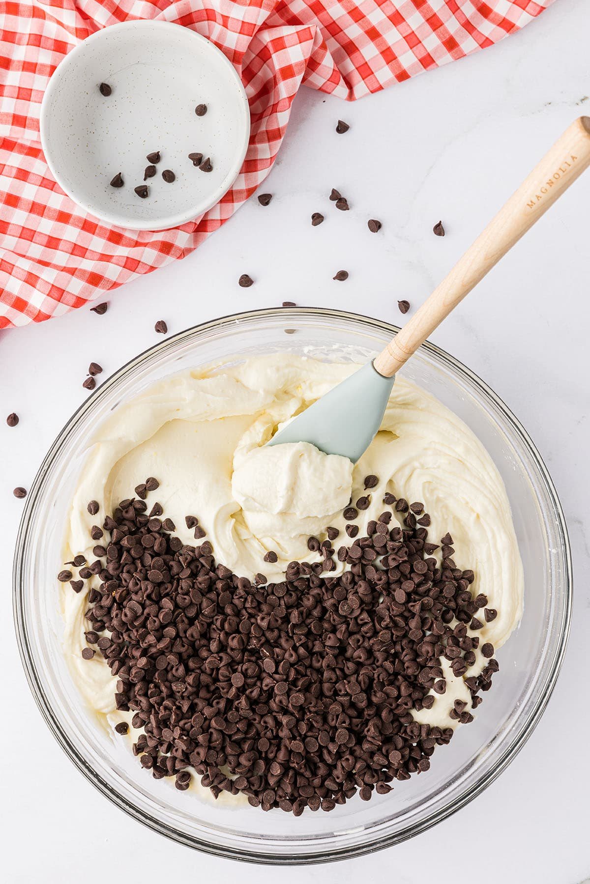 dessert dip with chocolate chips in glass bowl with red and white checked towel on the counter