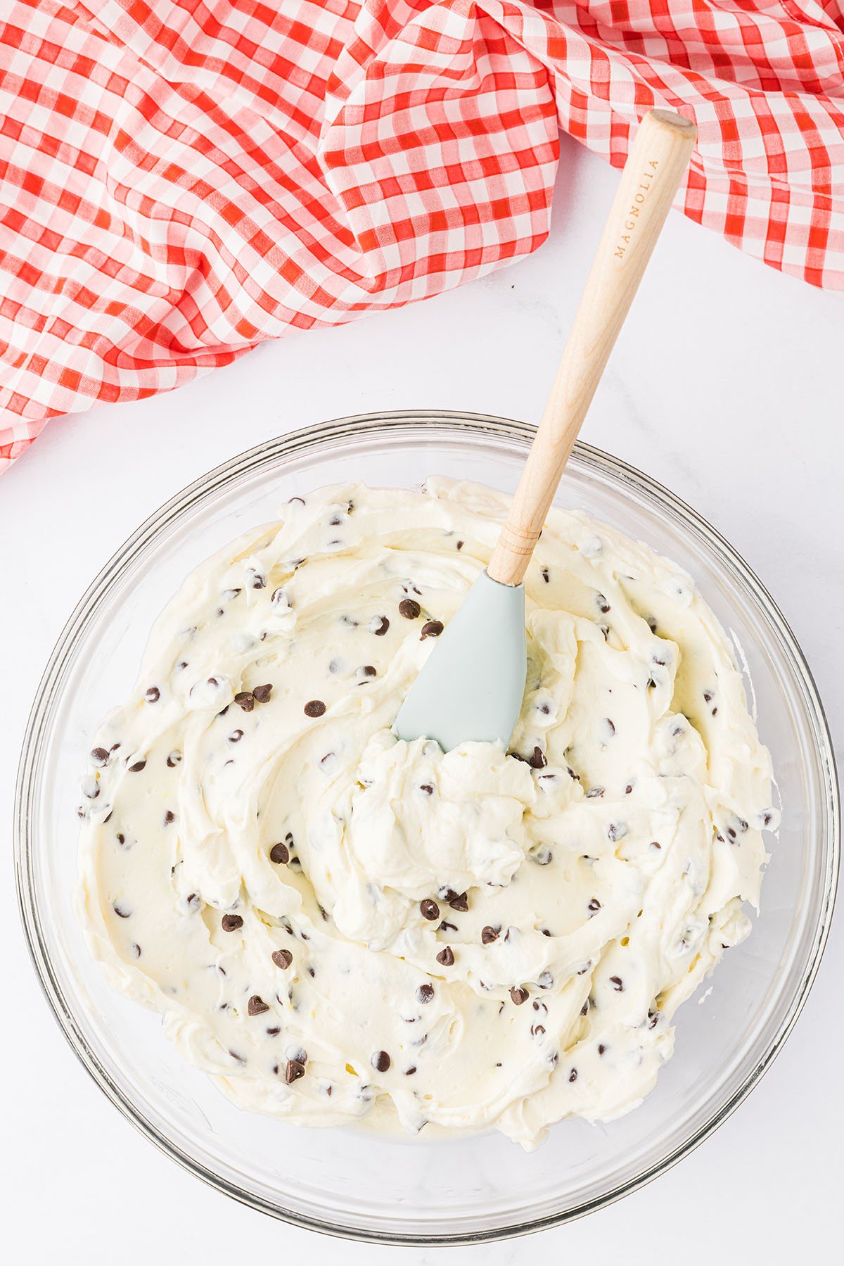 cannoli dip in glass bowl with red and white checked towel on the counter