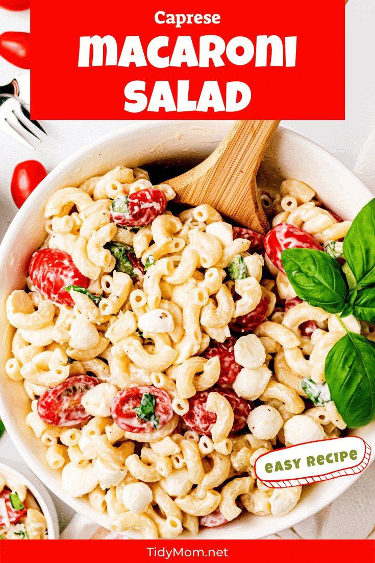 Creamy Caprese Macaroni Salad in a white bowl with a wooden spoon