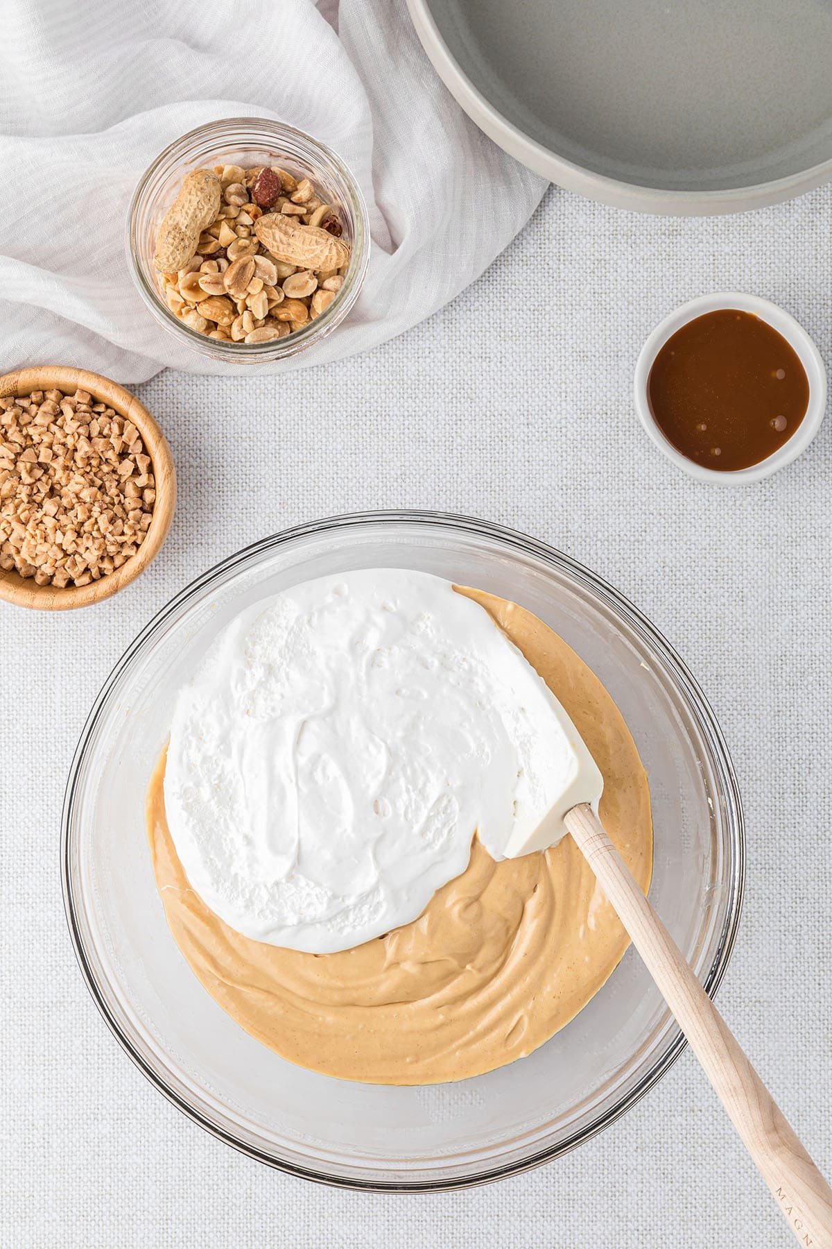 folding in marshmallow creme to caramel apple dip in a glass bowl
