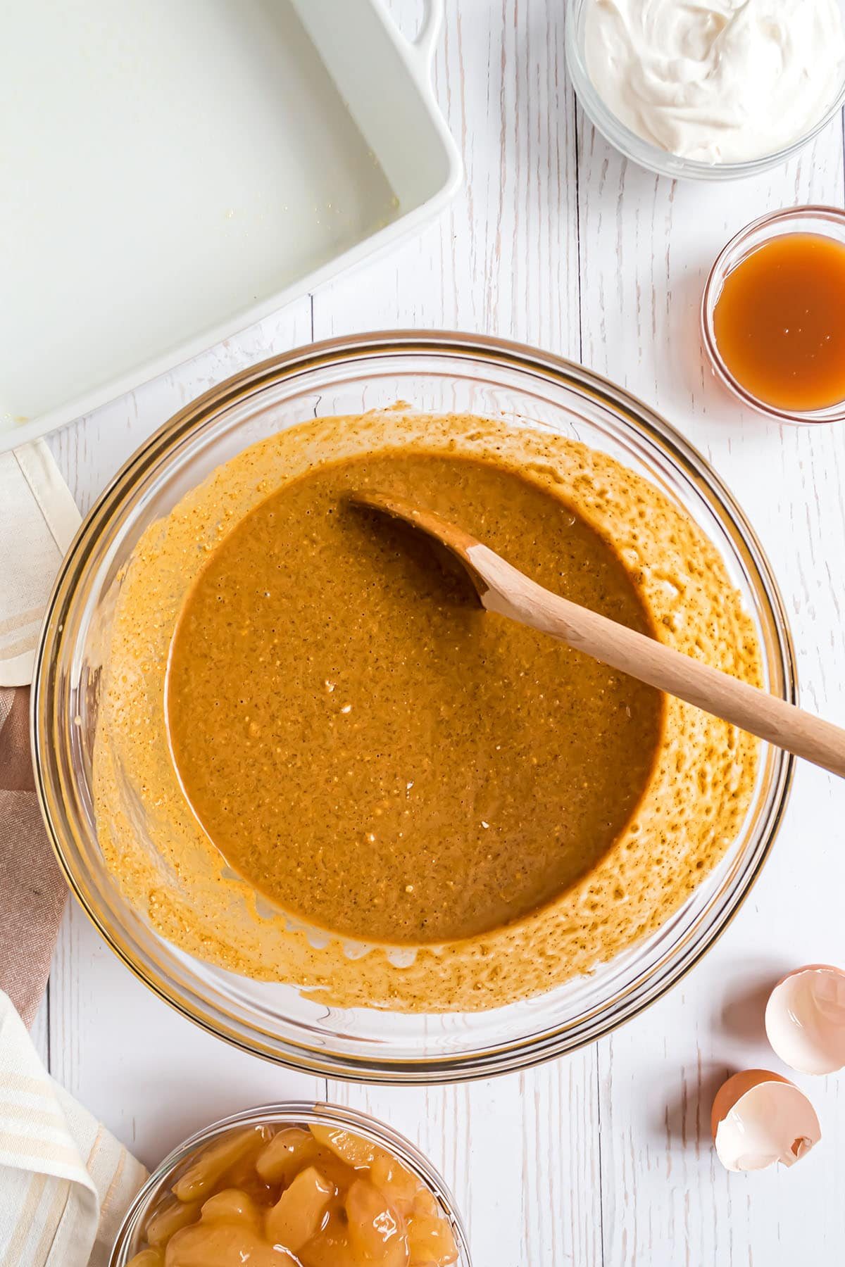 cake batter in a glass mixing bowl and a wooden spoon