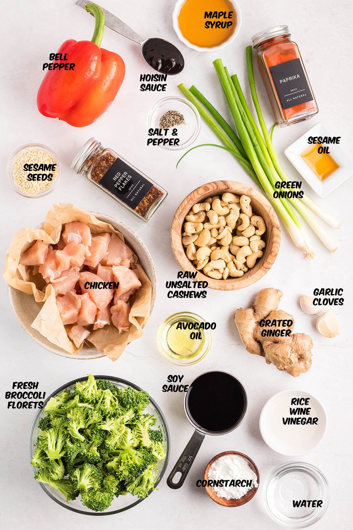 Overhead photo of Cashew Chicken Stir Fry ingredients on a countertop — chicken, broccoli, red peppers, garlic, ginger, soy sauce, and cashews.