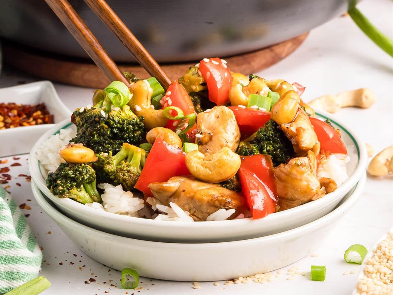 Cashew Chicken Stir Fry served over white rice with chopsticks — tender chicken, crisp vegetables, and cashews coated in a glossy, savory-sweet sauce.