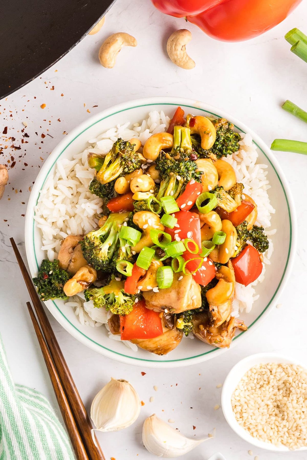 Overhead shot of Cashew Chicken Stir Fry served over white rice with chopsticks — tender chicken, crisp vegetables, and cashews coated in a glossy, savory-sweet sauce.