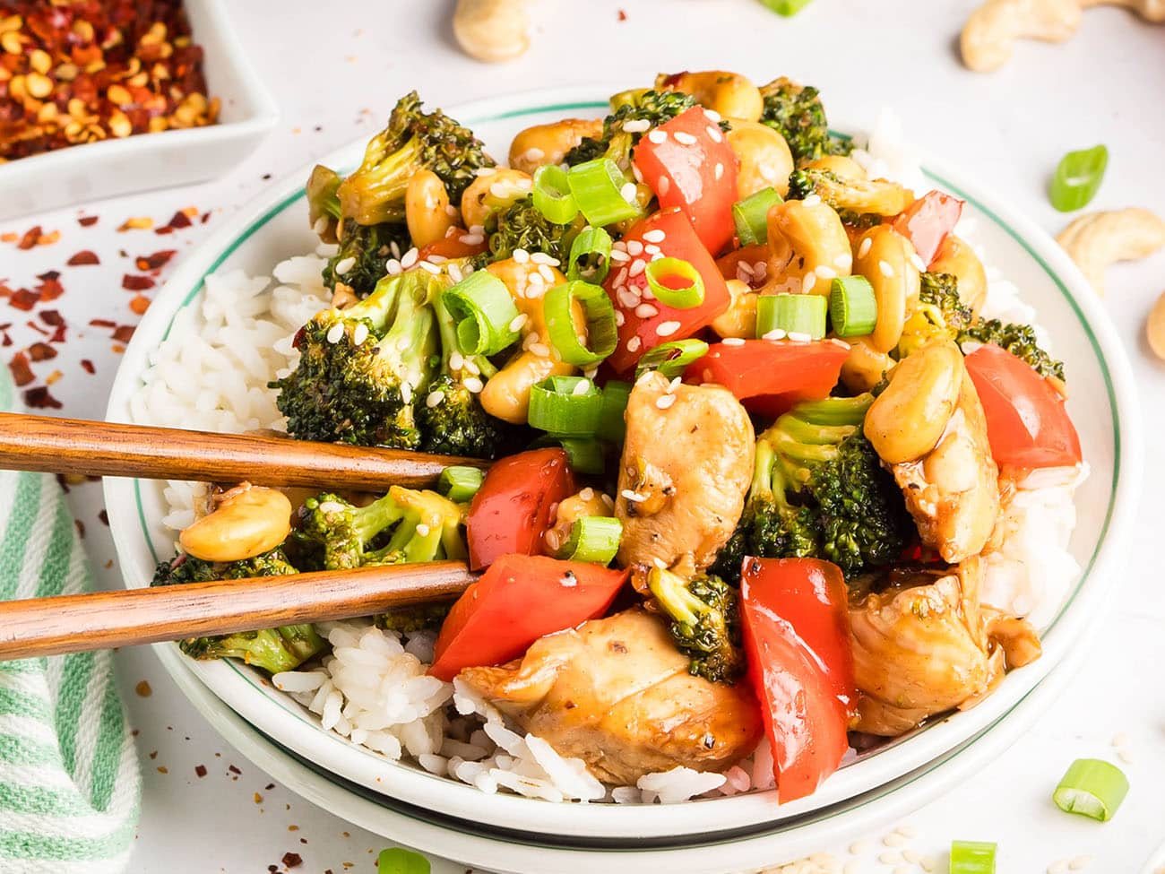 Cashew Chicken Stir Fry served over white rice with chopsticks — tender chicken, crisp vegetables, and cashews coated in a glossy, savory-sweet sauce.
