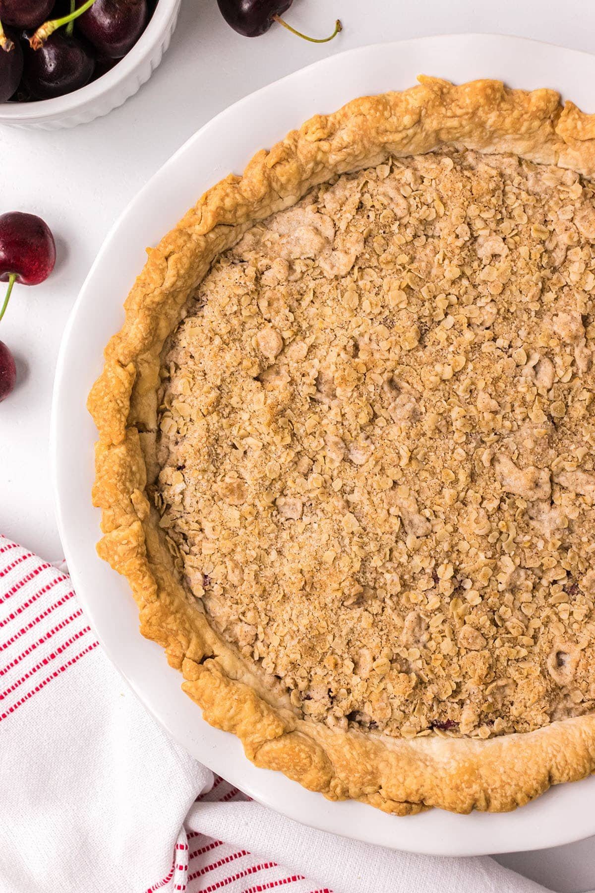 Uncut Cherry Crumb Pie in a white pie dish