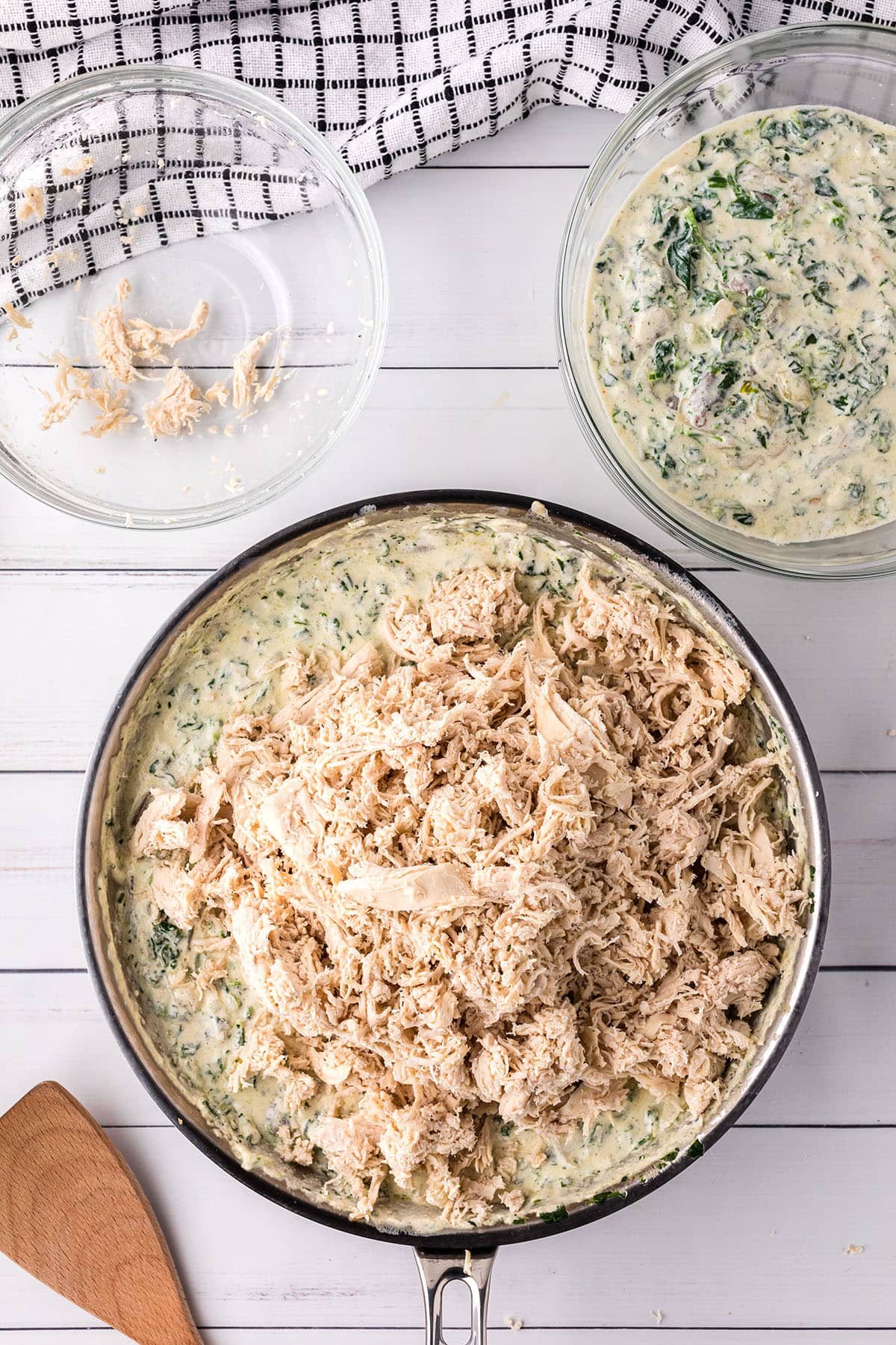 making creamy white sauce with chicken in a skillet for enchilada casserole