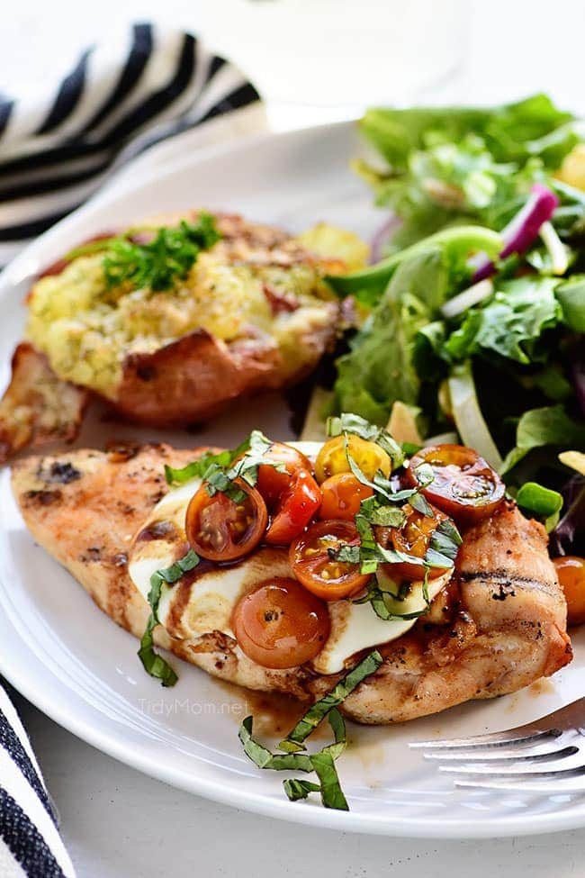 Dinner plate with caprese topped chicken, salad and potoates