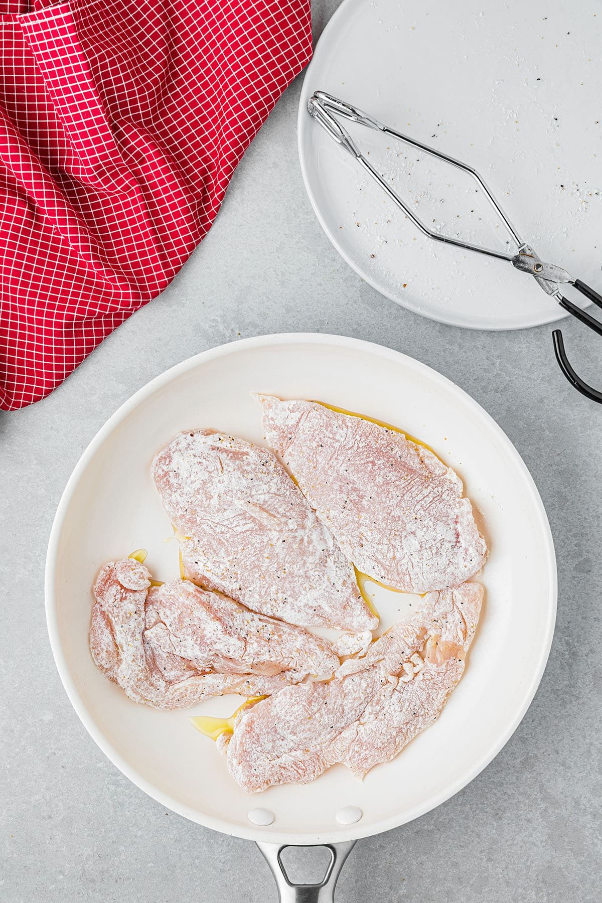 flour coated chicken breasts in a skillet