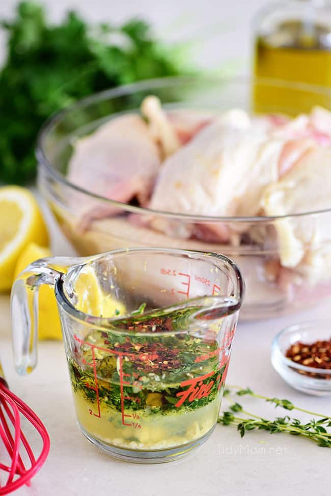 lemon herb chicken marinade in measuring cup with raw chicken