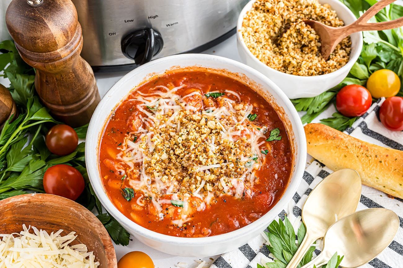 Bowl of Slow Cooker Chicken Parmesan Soup topped with toasted breadcrumbs and melted Parmesan cheese.