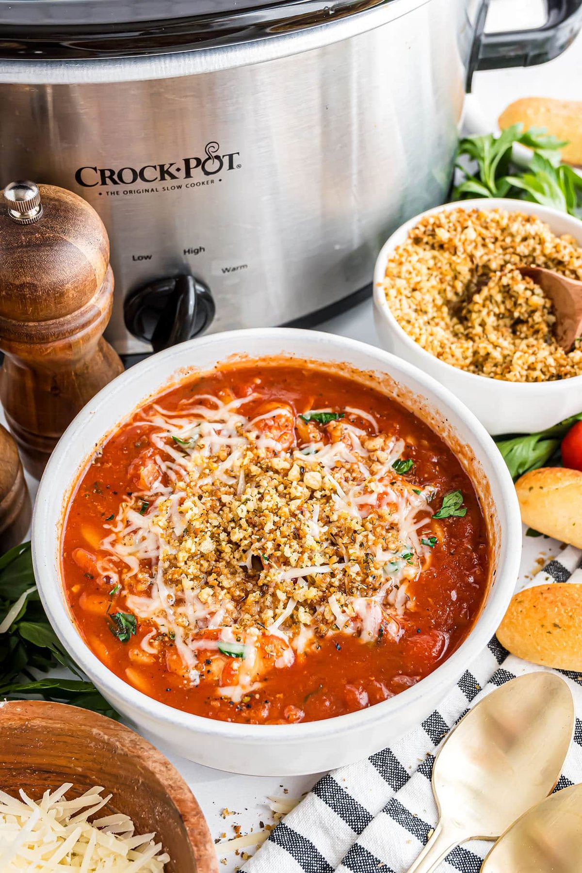 Chicken Parmesan Soup in a white bowl by a slow cooker