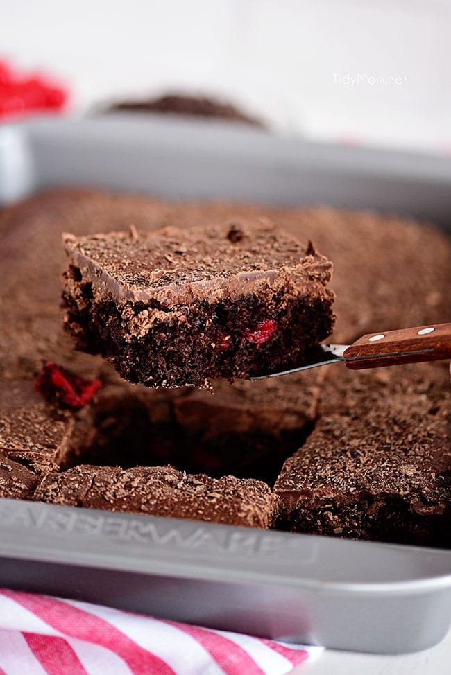 a cut piece of chocolate cherry cake coming out of the pan