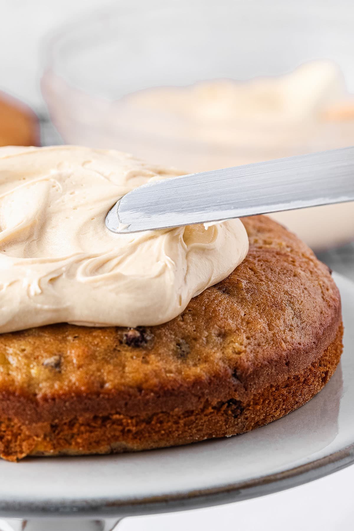 spreading frosting on the first layer of banana cake.