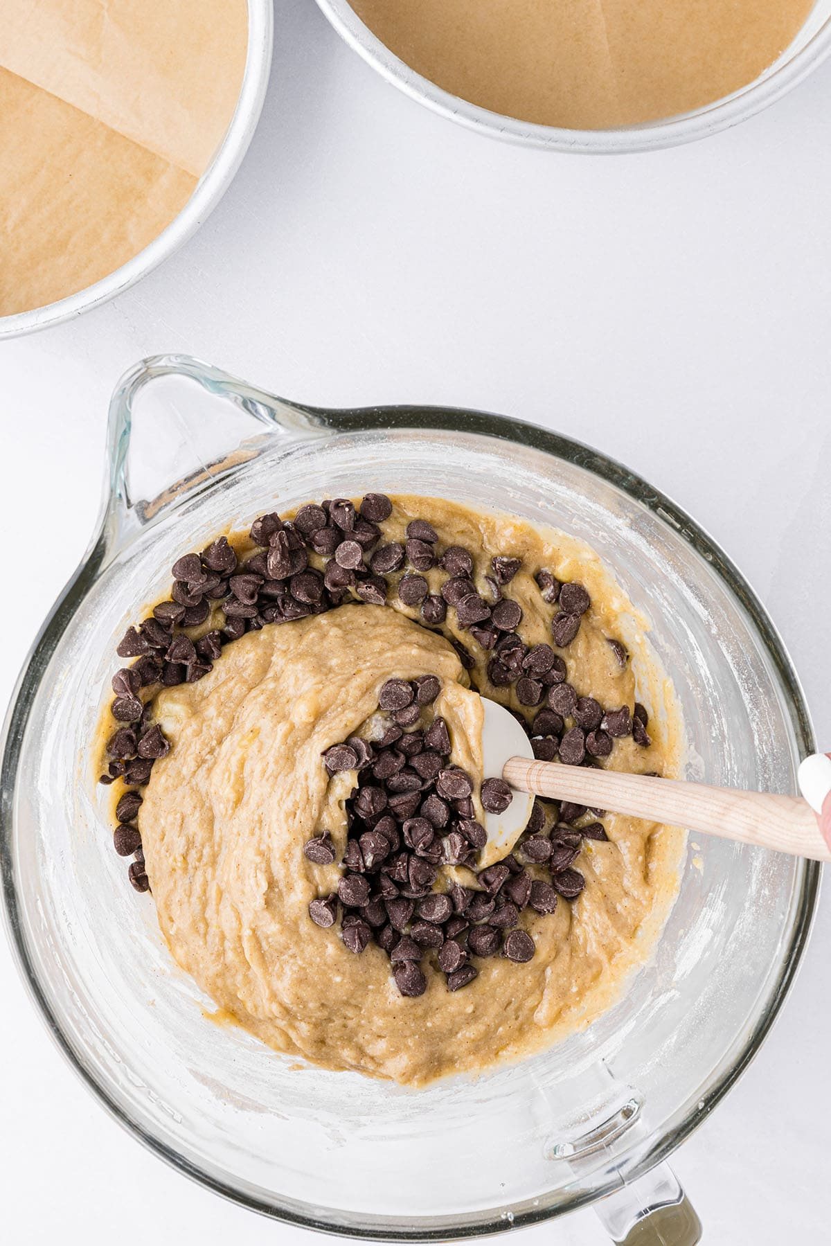 banana cake batter and chocolate chips in a glass mixing bowl