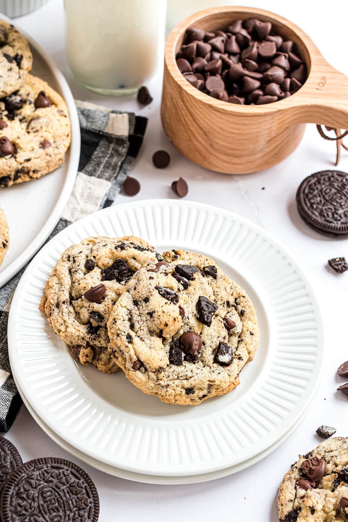 Oreo filled chocolate chip cookies on white plates with a black and white napkin