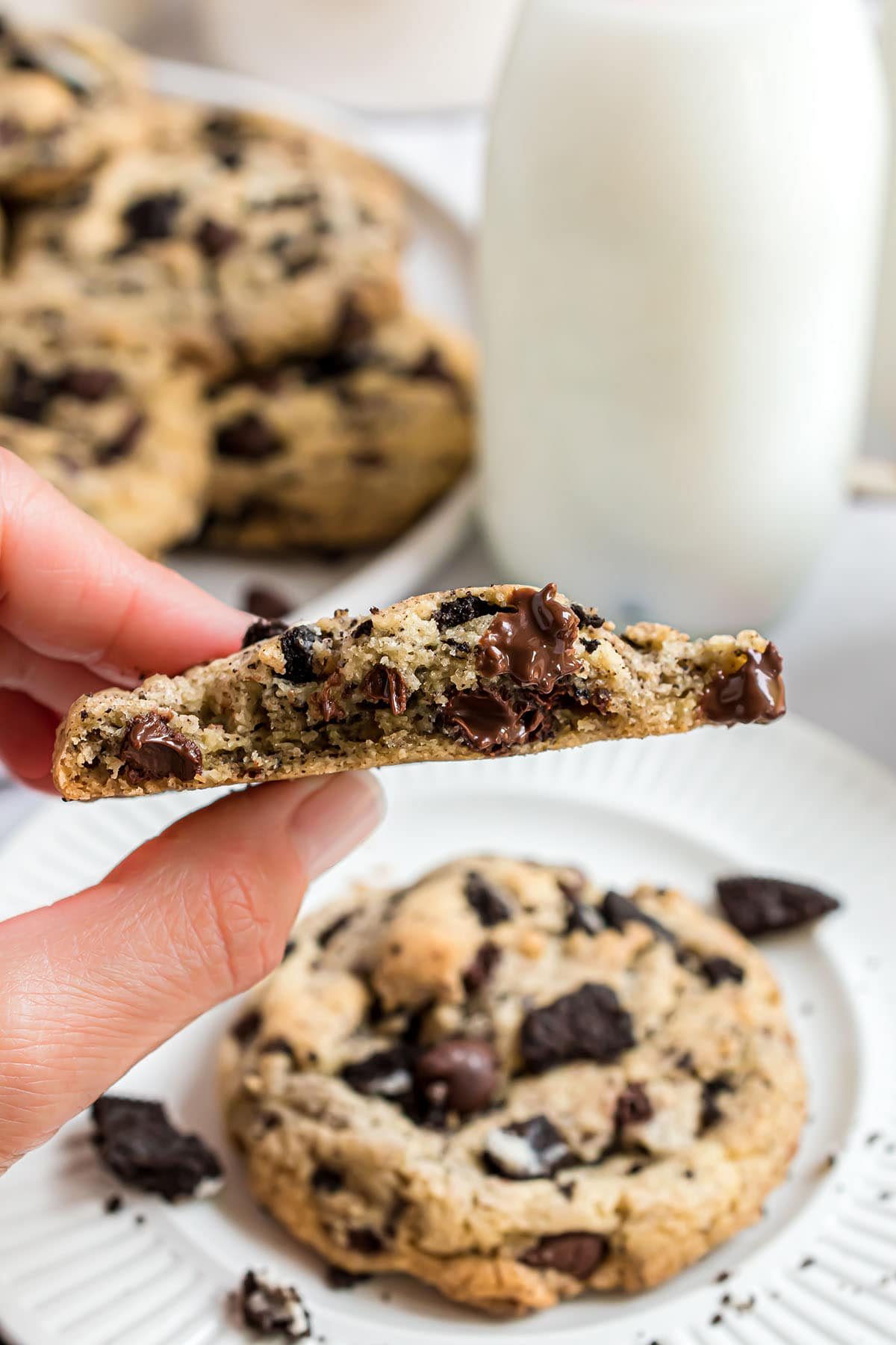 woman's hand holding a Chocolate chip Oreo cookie broke in half