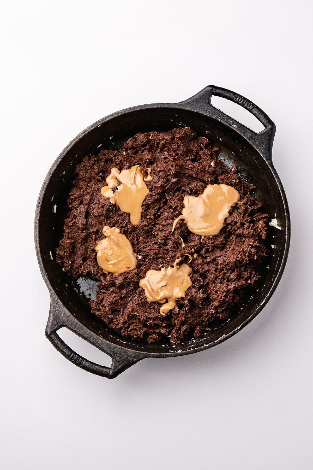 Dollops of peanut butter on chocolate cobbler batter in a skillet