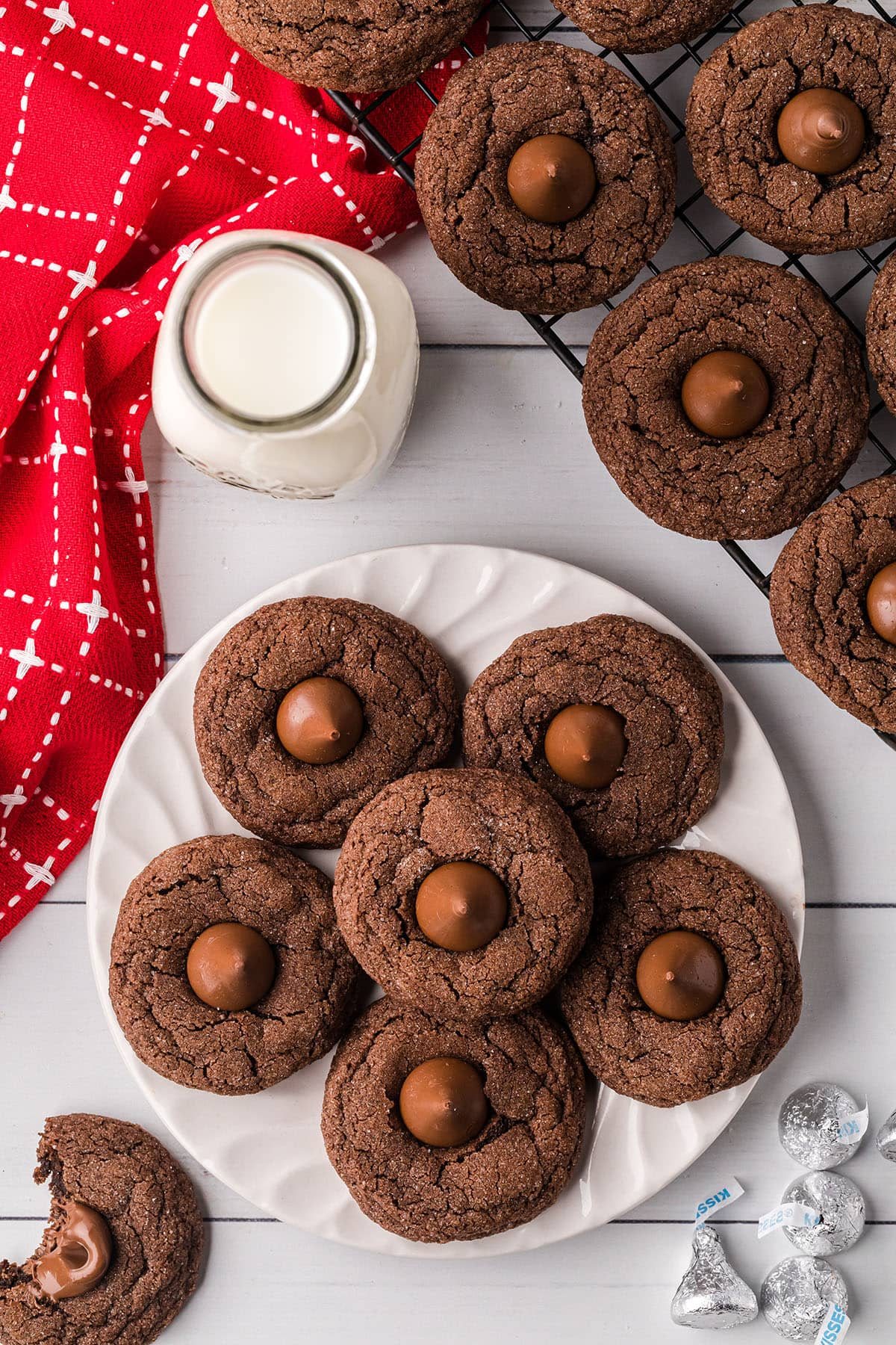 chocolate kiss cookies on a white plate with milk and a red napkin