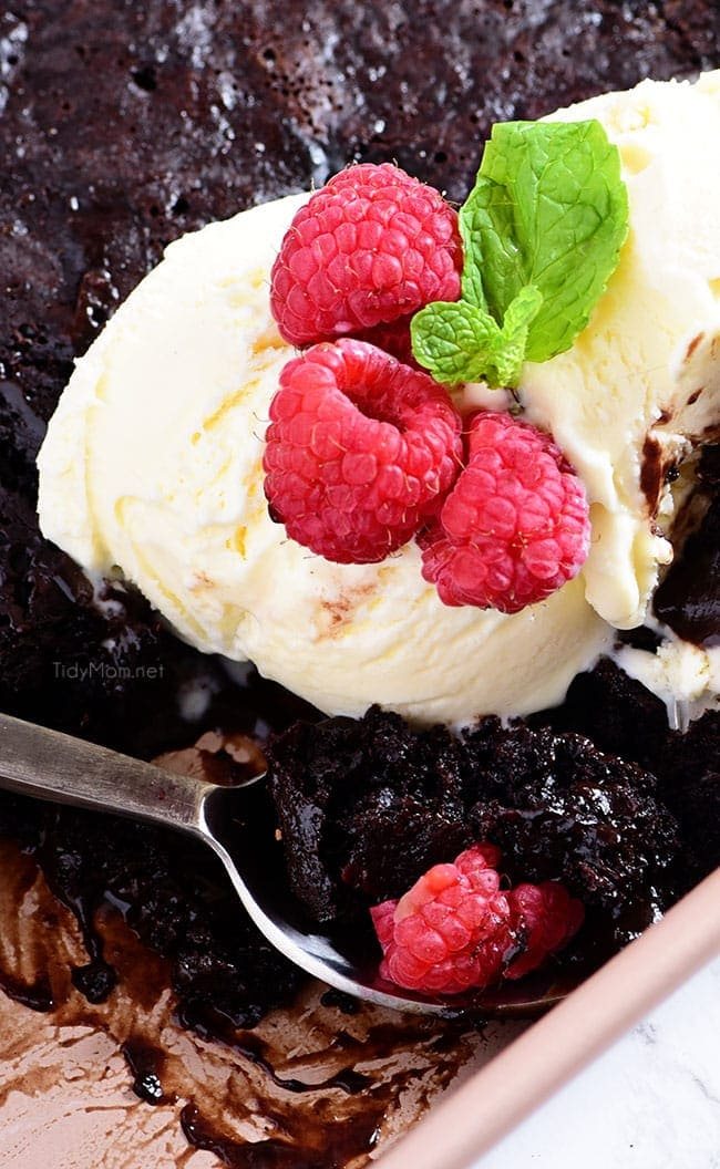chocolate lava cake in the pan topped with ice cream and rasberries