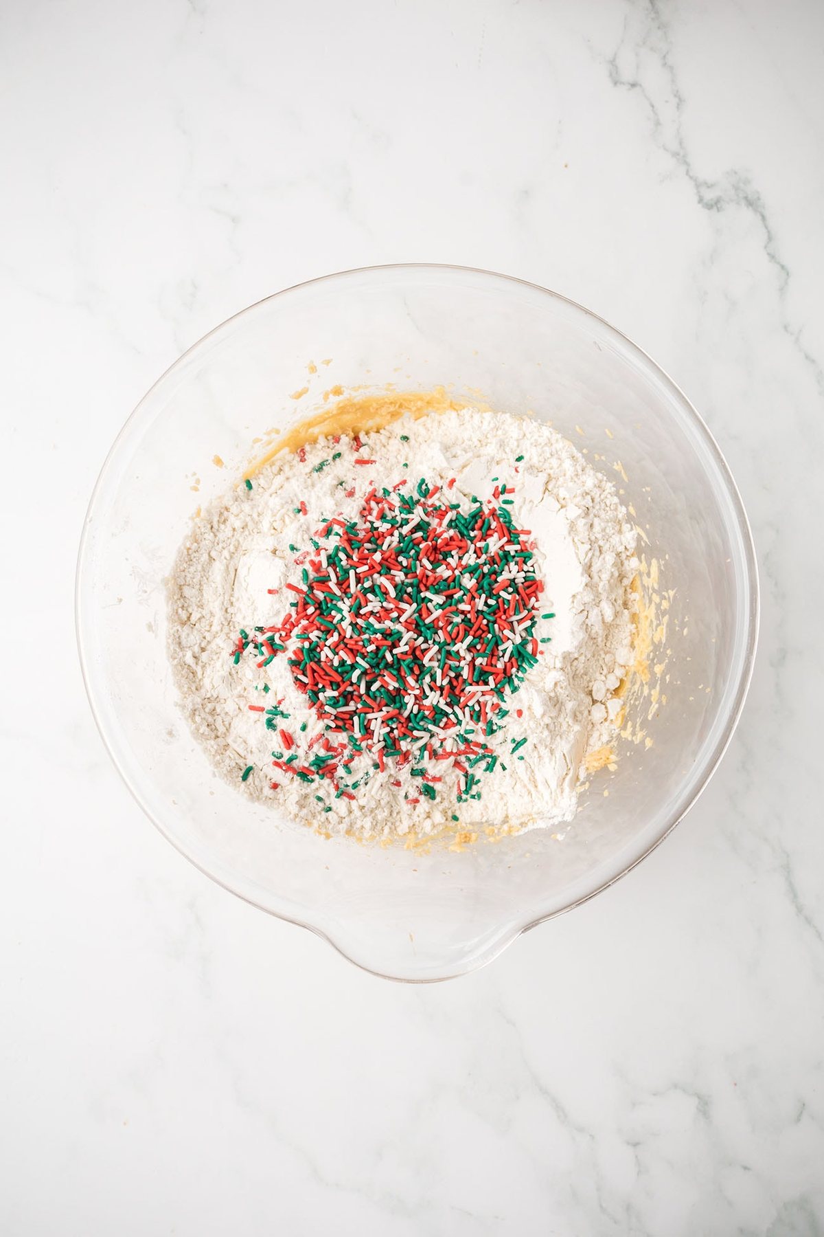 Blondie batter being mixed with flour and holiday sprinkles.