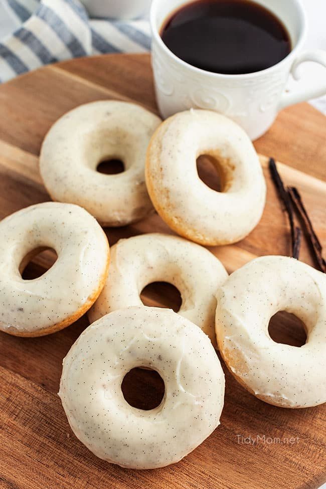 a pile of cinnamon donuts on a wood board with a cup of coffee