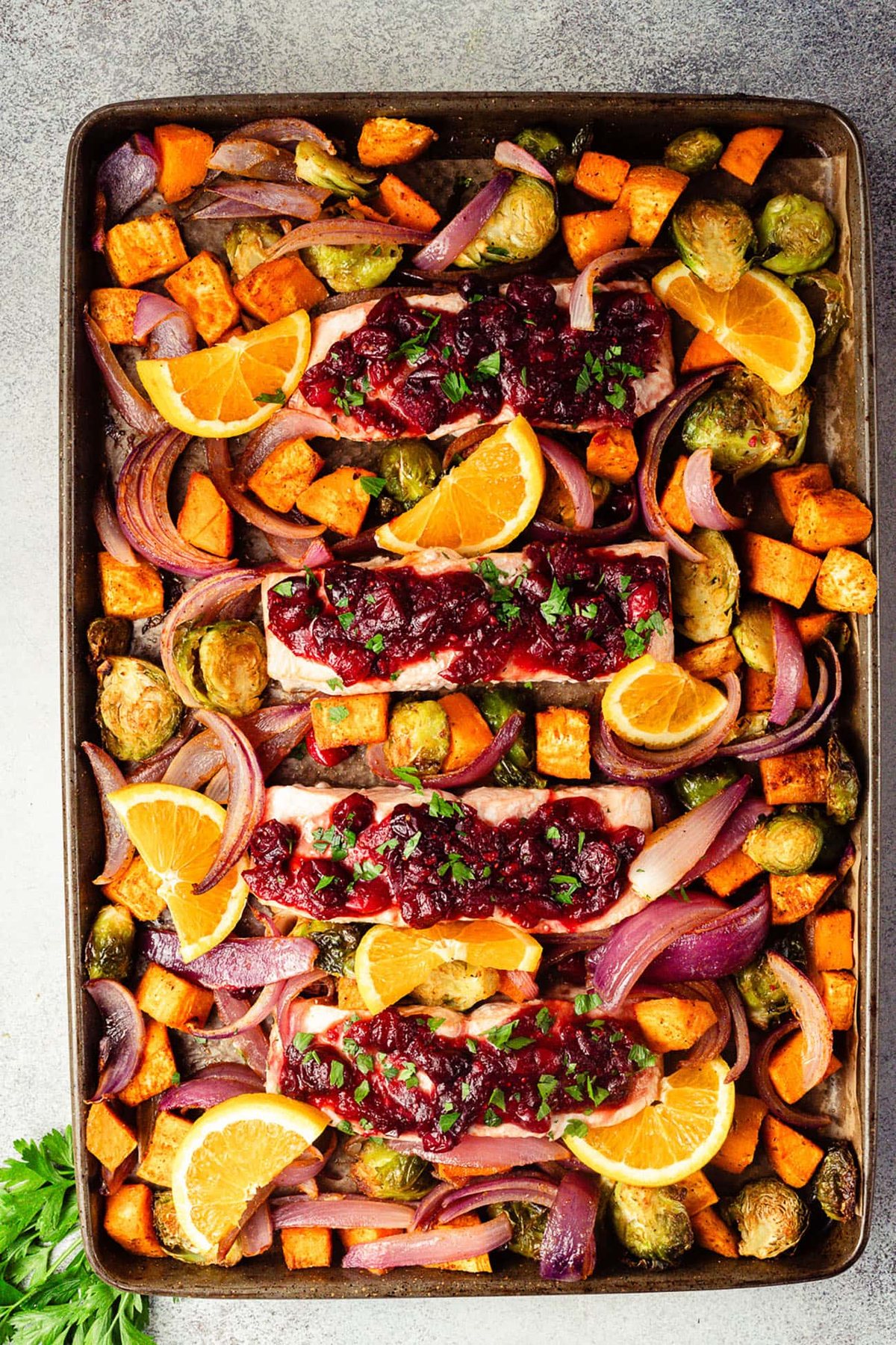 Baked cranberry orange glazed salmon with roasted vegetables and orange slices.