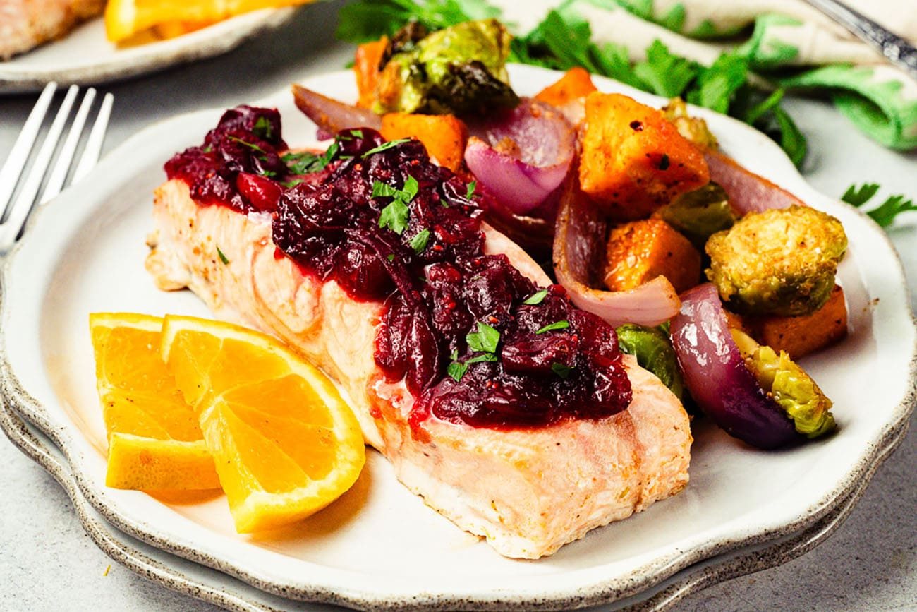 Cranberry orange glazed salmon served with colorful roasted vegetables.