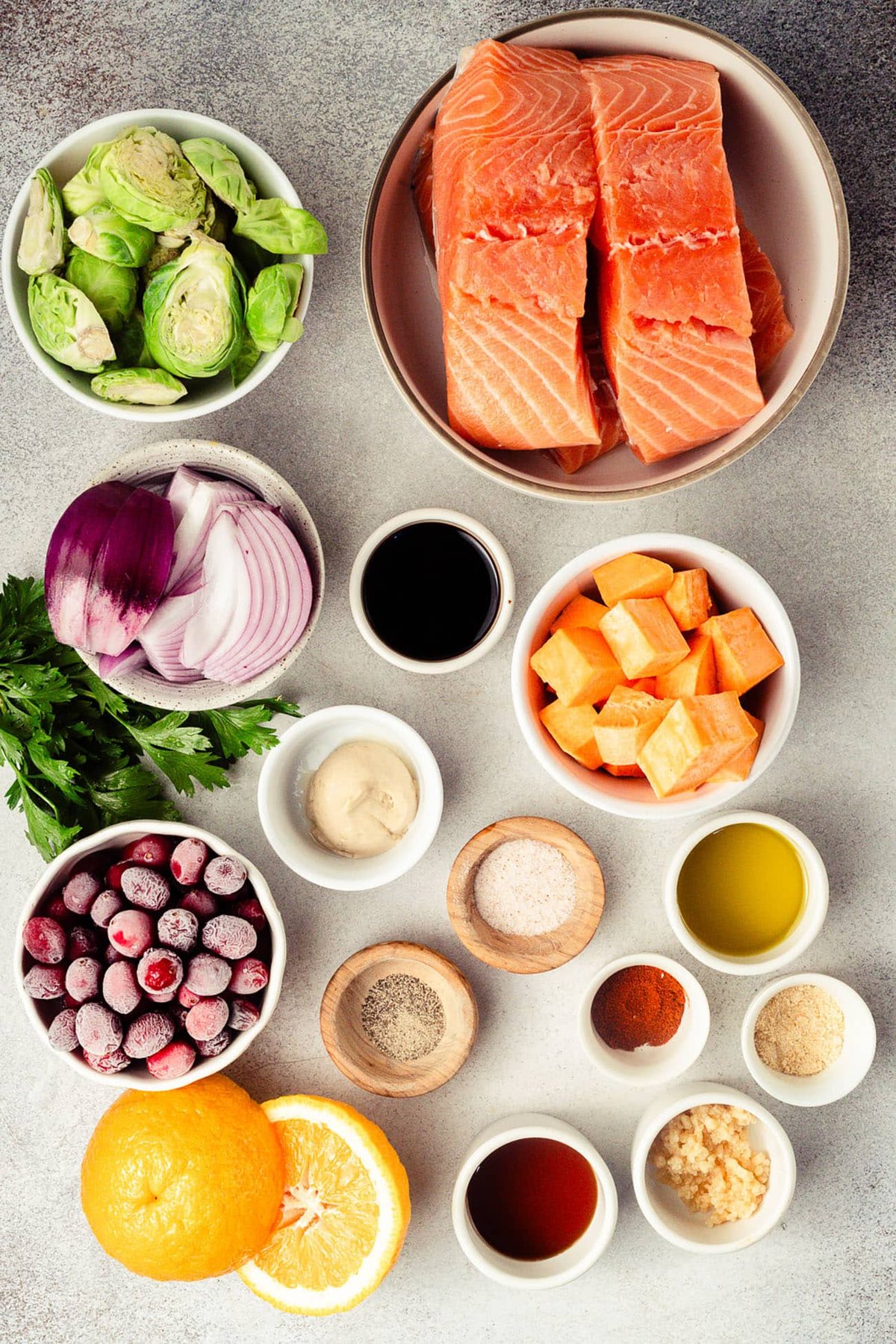 Ingredients for cranberry orange glazed salmon arranged on a gray surface.