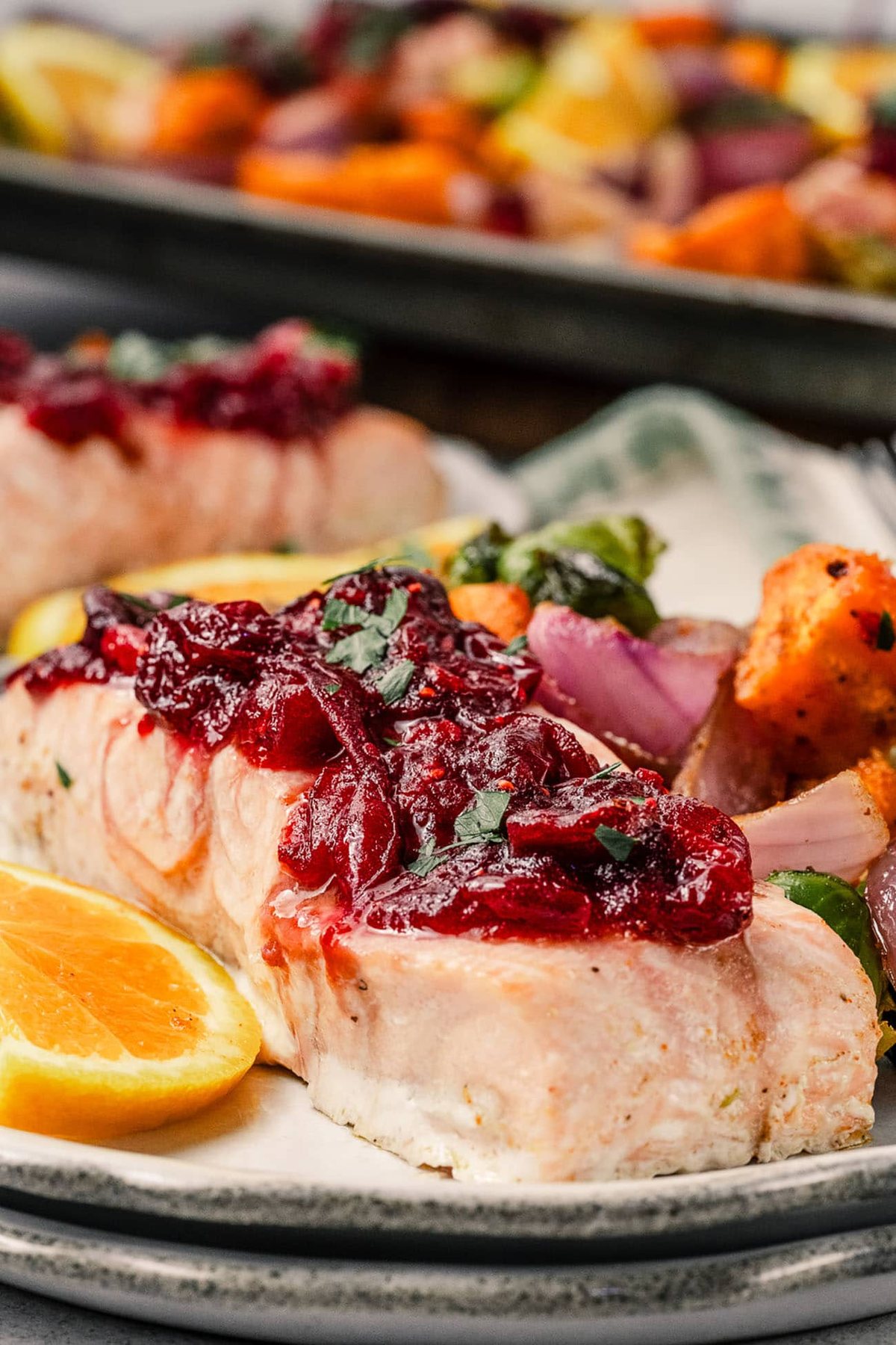 Plated cranberry glazed salmon with roasted sweet potatoes, Brussels sprouts, and red onion.