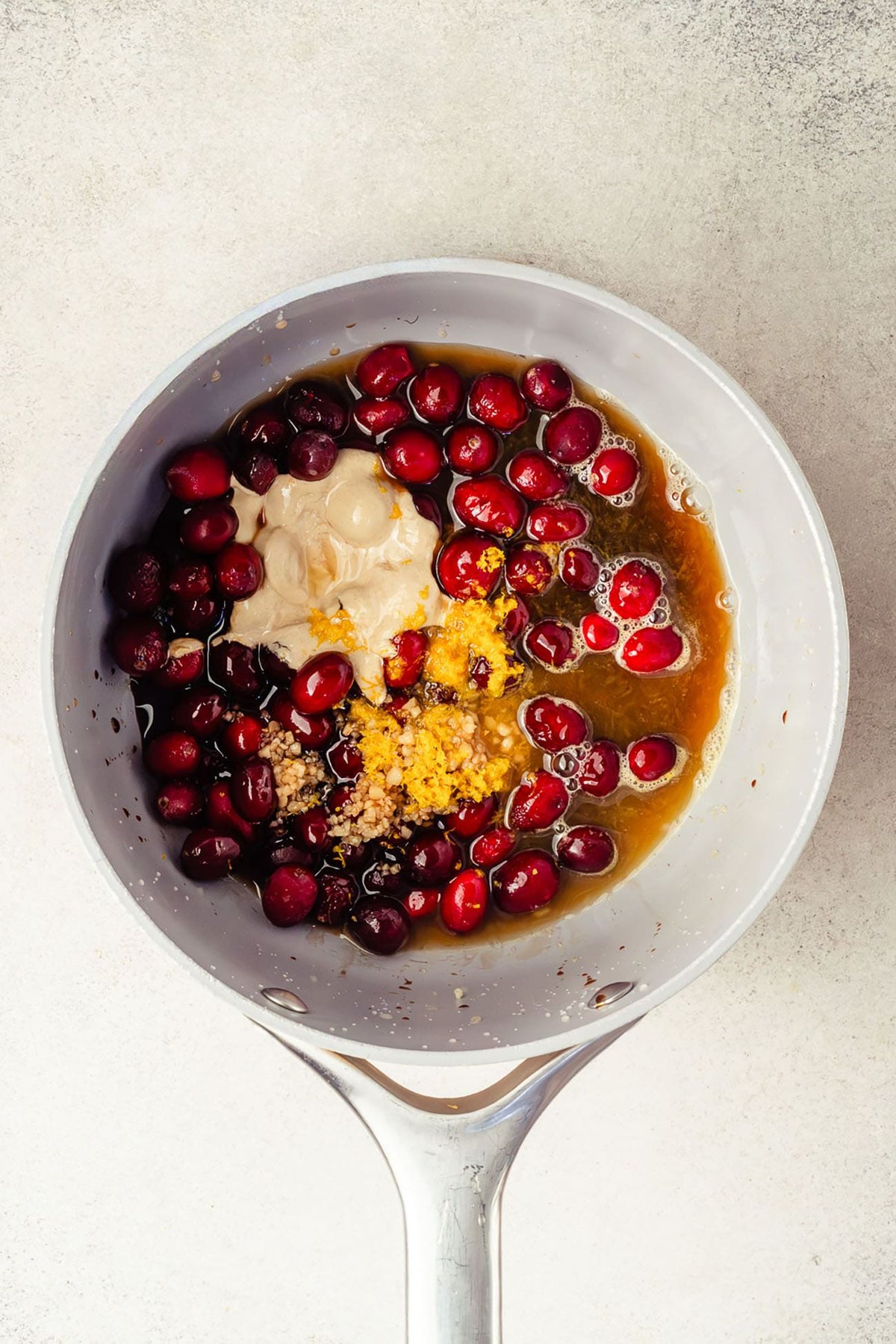 Cranberries, orange zest, garlic, and other glaze ingredients in a saucepan.
