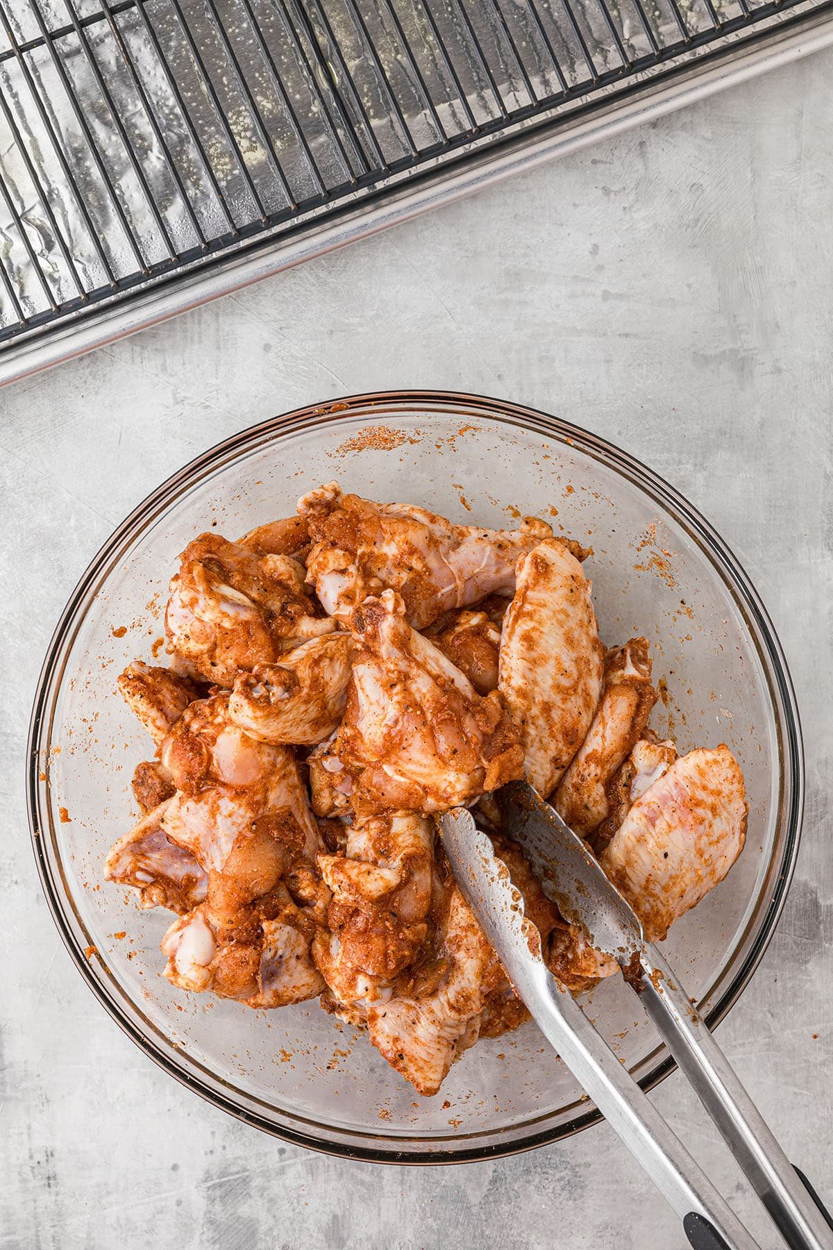 seasoned chicken wings in a glass mixing bowl