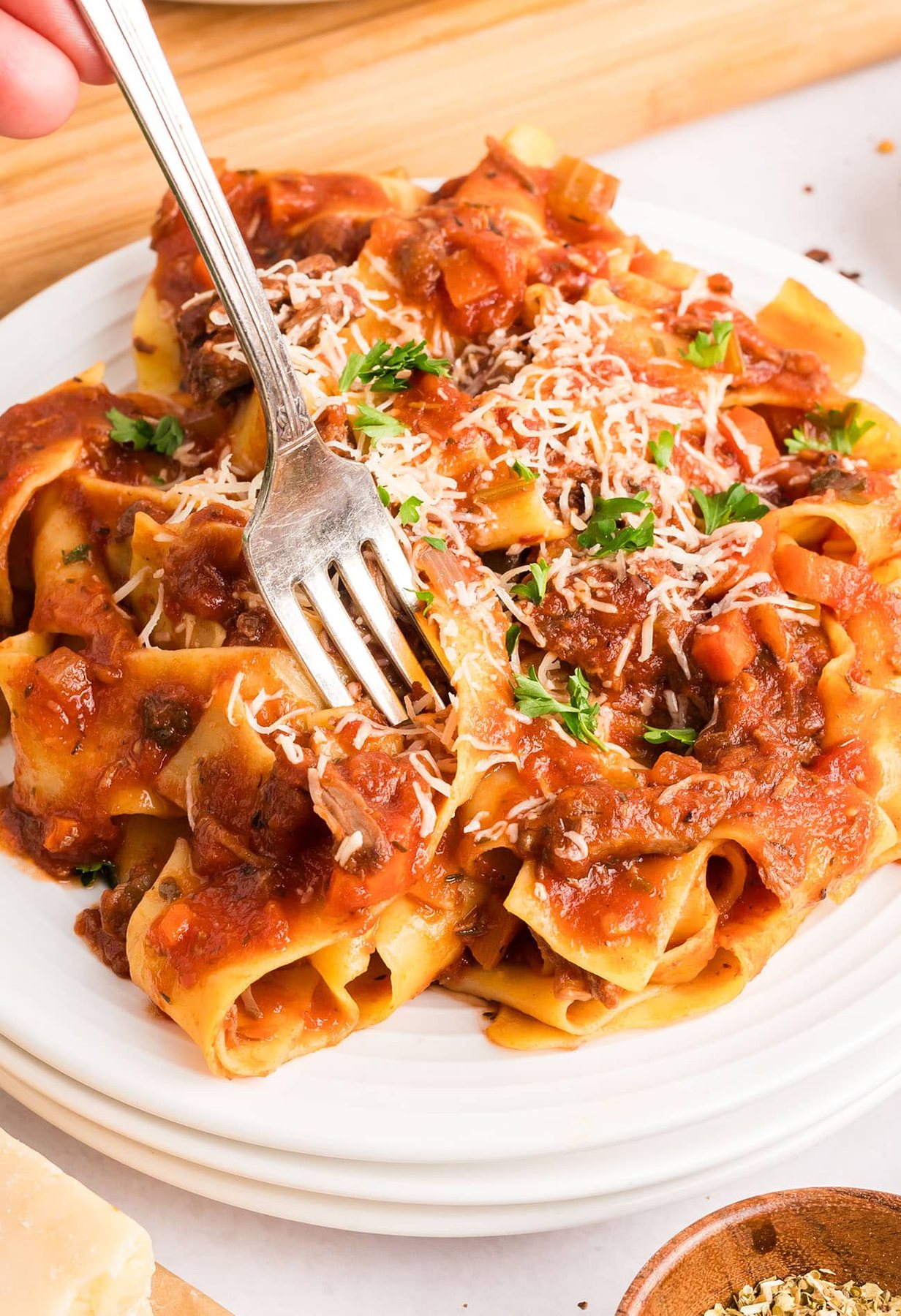 plate of ragu over pasta with a fork.